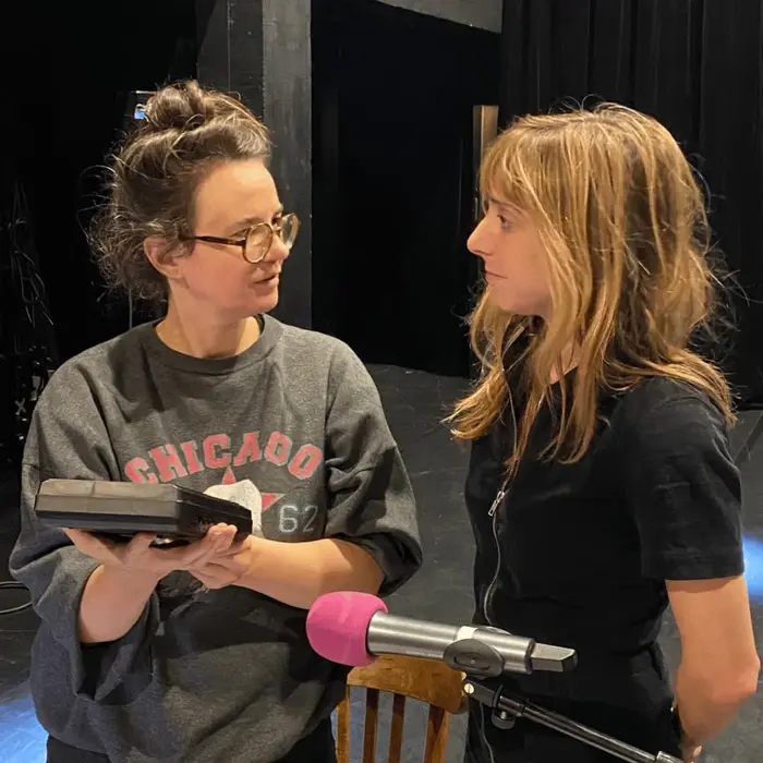 On voit deux femmes de face. A gauche, Mélanie Péclat et à drite Lucie Rico. Elles sont autour d'une table où il y a des consoles et un micro car elle vont faire une lecture performée.
