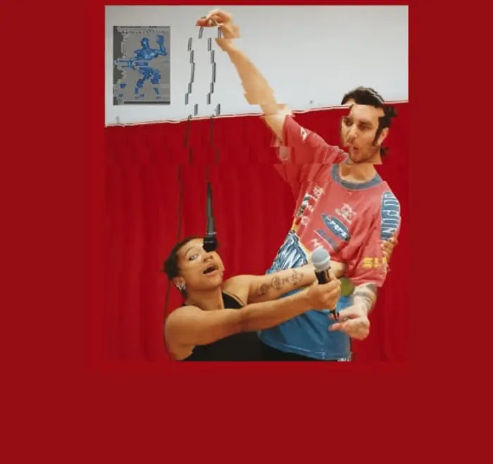 Deux personnes sont au centre de l'image : une femme qui a l'air d'être assise et un  homme debout. Ils nous font face. Ils tiennent chacun un micro dans leurs mains. L'homme tient en hauteur le micro dans lequel la femme chante et la femme tient le micro vers ce qui semble être devant elle. L'image est diffractée à plusieurs endroits dont ça ne permet pas une lecture claire du propos.