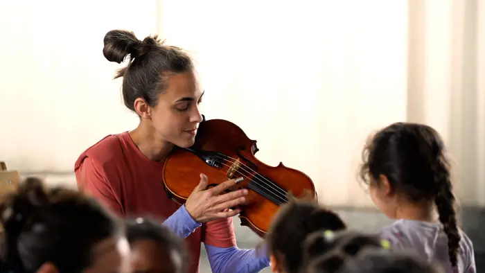 Sur ces images on voit Julie Michael qui joue de l'alto en compagnie d'enfants.
