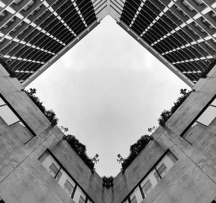 Il s'agit d'une photo en noir et blanc donnant sur le ciel. La photo est prise depuis le bas d'immeubles donc le ciel est cadré par les murs des immeubles.