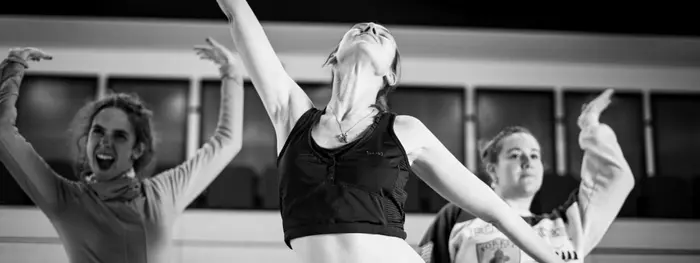 3 femmes sont en train de danser ou de faire une pose chorégraphiée. Elles ont les bras en l'air. N'apparaissent que leurs bras, leur visage et leur poitrine.