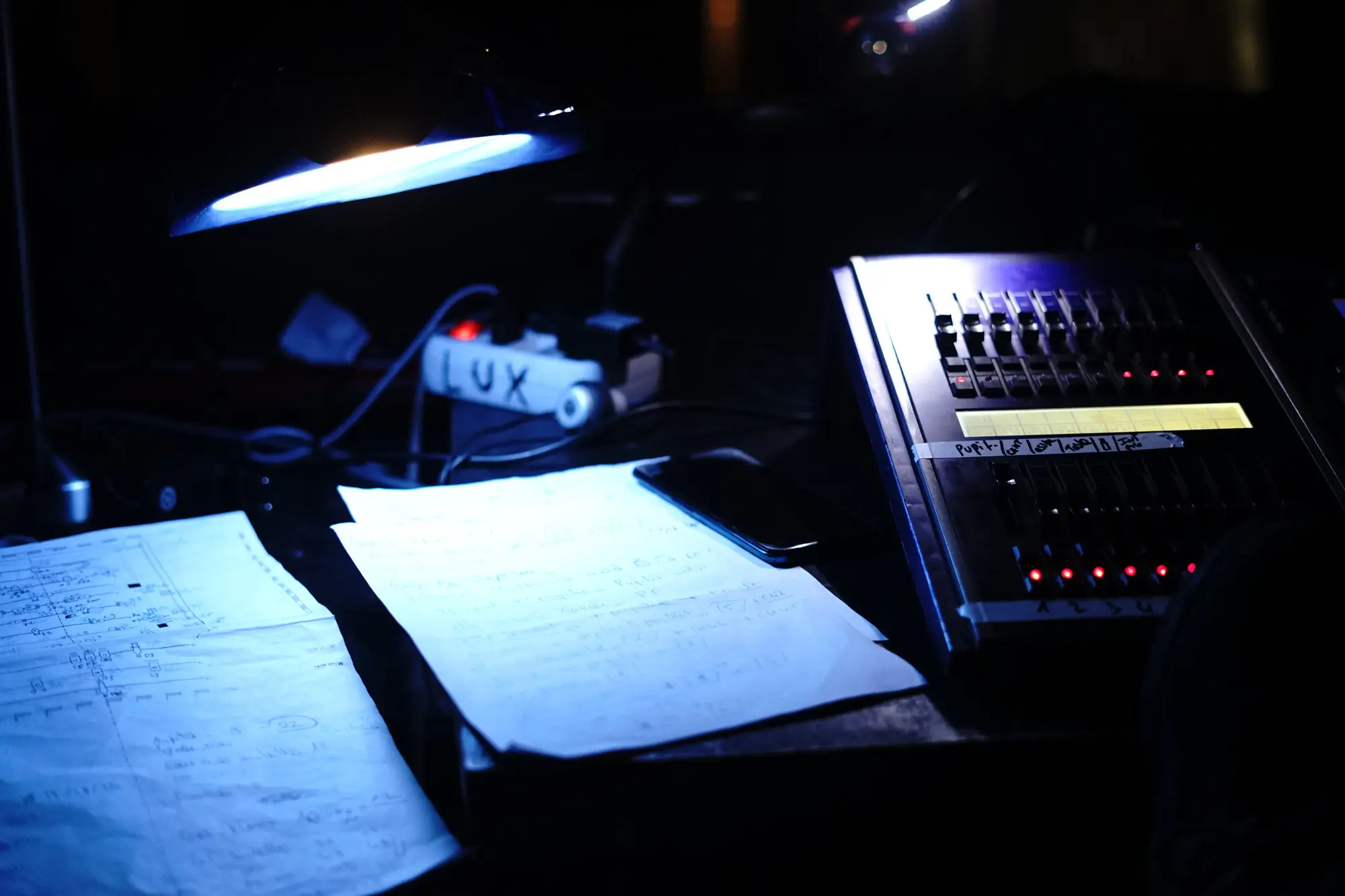 La photo a été prise en régie. C'est là où les techniciens et les techniciennes gèrent le son et les lumières. Il y a sur la photo, une console lumière et des fiches technique.