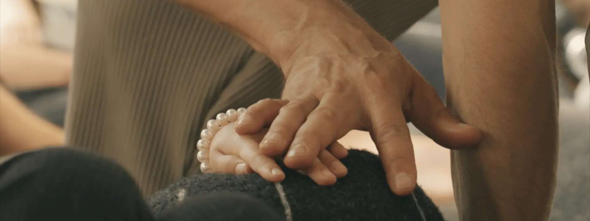 Sur cette image on voit deux mains qui se touchent, une d'entre elles est celle d'un enfant, l'autre est celle d'un adulte. On devine que ces mains sont posées sur un coussin galet.
