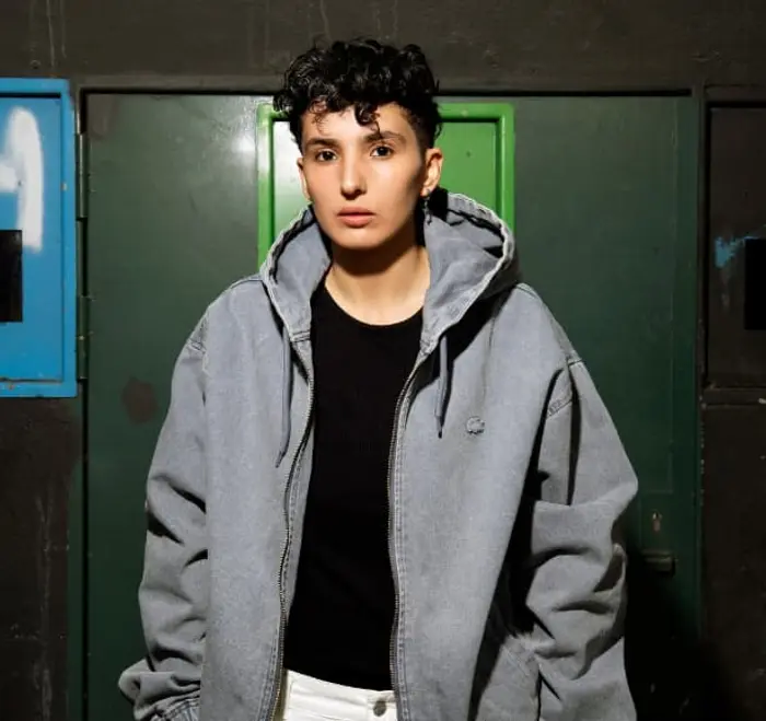 Sur cette photo, Fatima Daas. Elle porte une veste à capuche grise et a les chveux courts. 